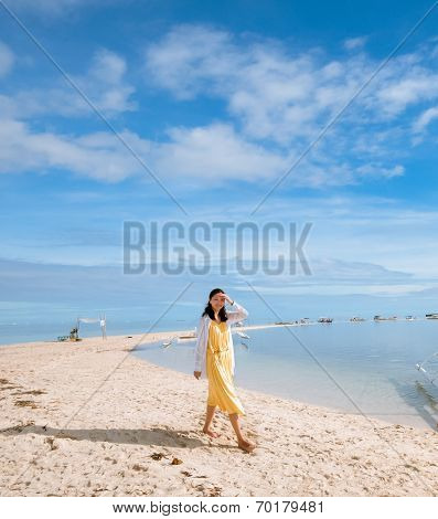 young girl walks on long narrow beach, smiling