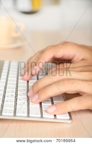Man working with keyboard on wooden table on folders background closeup