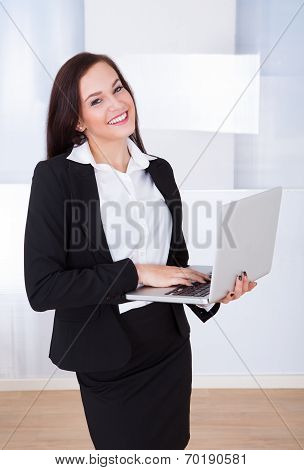 Welldressed Businesswoman Using Laptop In Office