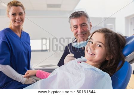 Smiling pediatric dentist and nurse with a young patient in dental clinic