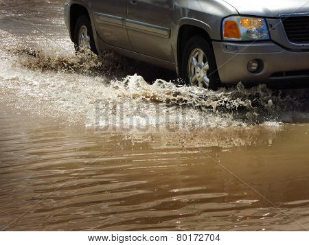 Detail of car driving through flood waters splashing