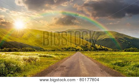 Abandoned Road Through Meadows In Mountain At Sunset