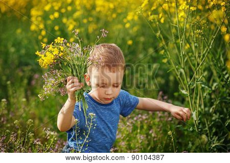 Cute Little Boy Running With A Bouquet Of Flowers On A Yellow Meadow