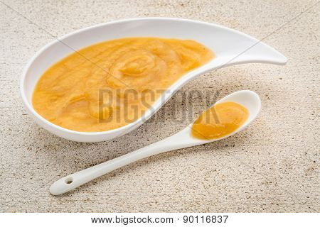 organic fruit and vegetable baby food or snack (apple, corn, sweet potato) - ceramic teardrop shaped bowl with a spoon on a grunge barn wood