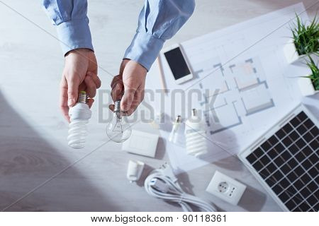 Man Comparing An Incandescent Bulb And A Cfl Lamp