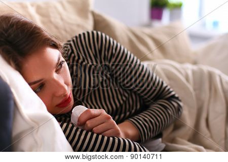 Portrait of a sick woman blowing her nose while sitting on the sofa