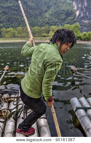 Girl Ferryman Crosses River On Bamboo Raft In Guilin, China