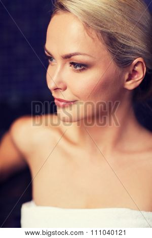 people, beauty, spa, healthy lifestyle and relaxation concept - close up of beautiful young woman sitting in bath towel