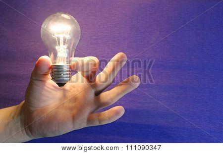 Lighting lamp flashing bulb in human hand on blue background