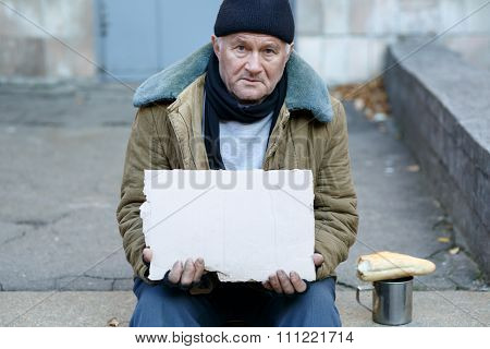 Homeless man holding a cardboard sign.