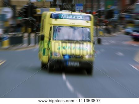 Emergency ambulance travels through city street. Zoom effect applied for dramatic effect.