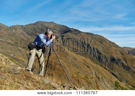Professional photographer making landscape photos by digital mirror camera and tripod at rock mountainon