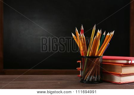 School equipment on desk on blackboard background
