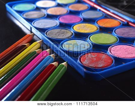 Pallette of water colors and colored pencils