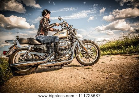 RUSSIA-JULY 7, 2013: Biker girl and bike Harley Sportster. Harley Davidson sustains a large brand community which keeps active through clubs, events, and a museum. Filter applied in post-production.