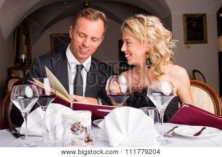 Couple at restaurant choosing what to eat from menu
