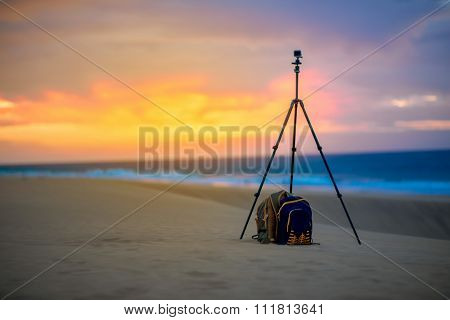 Small video camera on the tripod with backpack outside