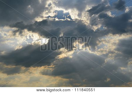 The sun's rays shine through the dark clouds.