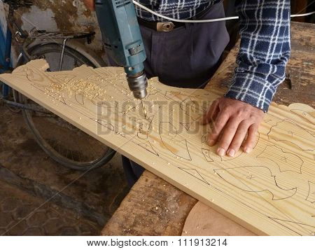 A Man With The Wooden Plate Preared To Drill Decoration