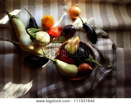 Black and white Aubergines, onions, red paprika set on striped linen cloth
