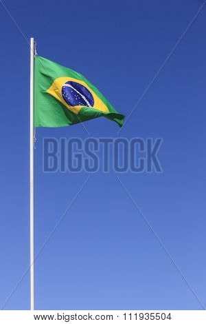 Brazilian flag waving on top of a flagpole in a clear sky day