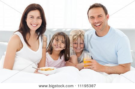 Família alegre com café da manhã juntos na cama