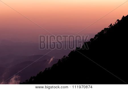 Silhouette of mountain slope Tajamulco with trees in front orange purple sunset