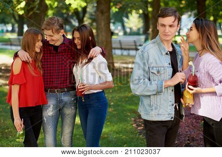 Jealousy and envy in friends relationship. Cheerful young people with detox cocktail having outdoor summer party