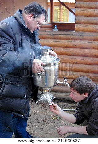 Agritourism. Rural tourism. Men trying to kindle the samovar.