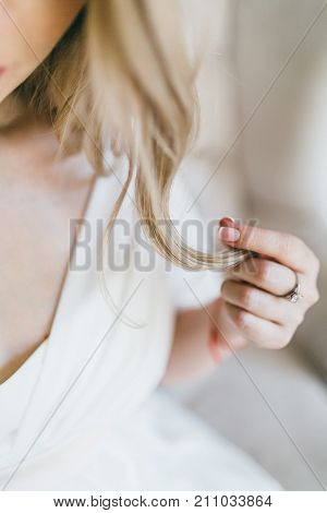 Wedding. Close up image of beautiful bride holds a earlock. Soft focus on a strand of hair. Artwork