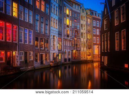 Illuminated houses over canal with reflections at night, Amstardam, Netherlands, retro toned