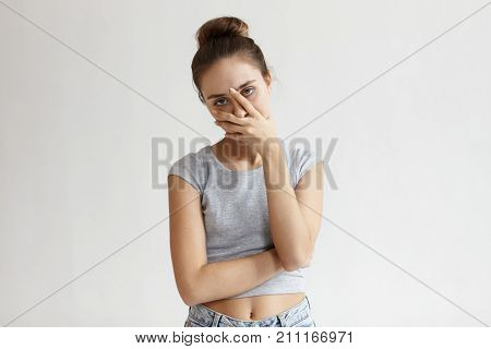 Portrait of annoyed stylish European girl wearing crop top with belly button showing making face palm gesture feeling bored while talking to her friend who speaking nonstop. Body language