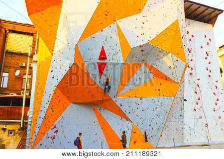 Kyiv, Ukraine - October 8, 2017: The young woman and men on rock wall in sport center outdoor at Kyiv, Ukraine on October 8, 2017