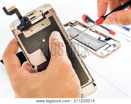 Close-up of technician being unlock screw with screwdriver on blurred smartphone component background