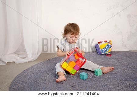 Little happy girl playing with toy on floor. Kindergarten.
