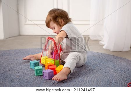 Little happy girl playing with toy on floor. Kindergarten.