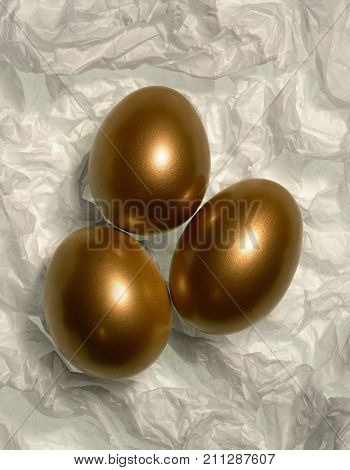 THREE GOLDEN EGGS ON WHITE TISSUE BACKGROUND