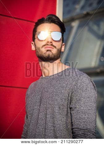 Attractive young bearded man portrait in urban setting, wearing sunglasses