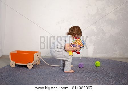 Little happy girl playing with toy on floor. Kindergarten.