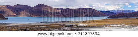 Panormaic view of holy lake Yamdrok with snowy mountains in the background- Tibet