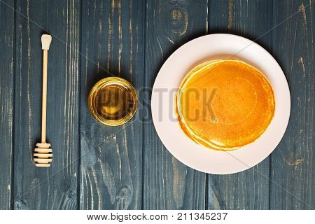 Stack of tasty pancakes with honey in jar