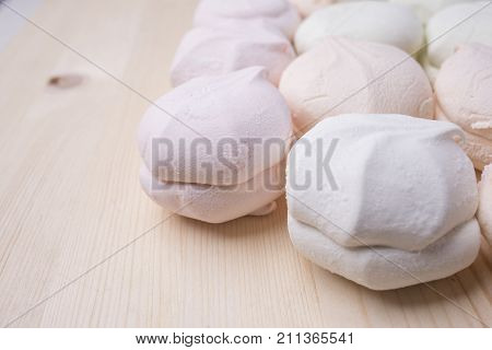 Multicolored marshmallow on a wooden background in the right part of the frame