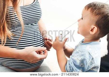 The Child Takes The Cigarette From His Pregnant Mother