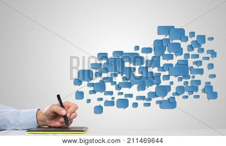 Hand of man using tablet and chatboxes flying out