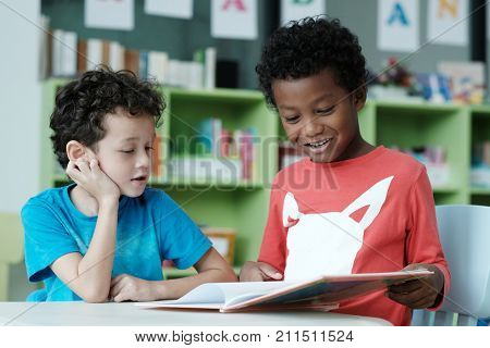 American and African boys are reading and studying together with happiness in their classroom kid education concept