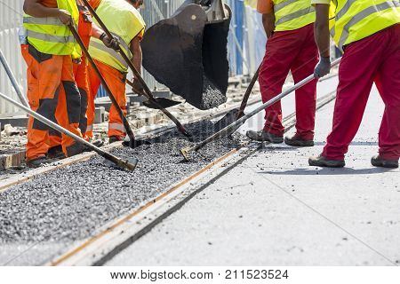 Workers Construct Asphalt Road And Railroad Lines