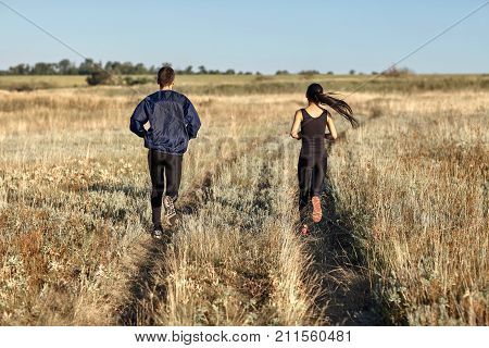 Back View Of Running Woman And Man Training In Field, Jogging