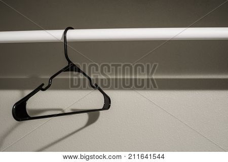 Single black coathanger on a closet rod