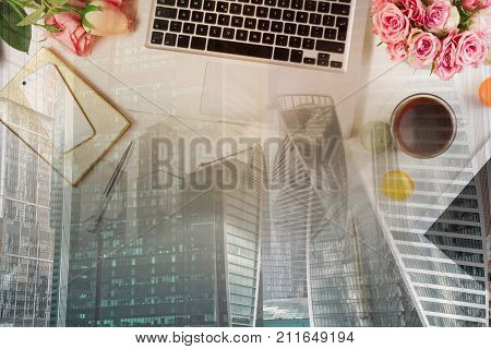 Feminine workspace - workspace with keyboard, coffee and flowers, double exposure with modern cityscape