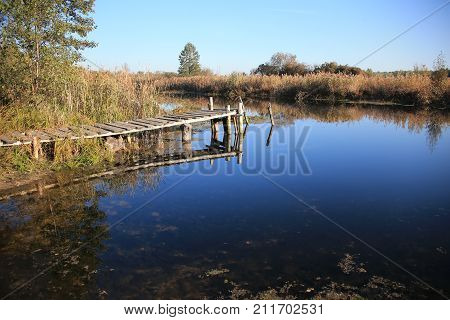 Old wooden bridge on a small river. Rural landscape